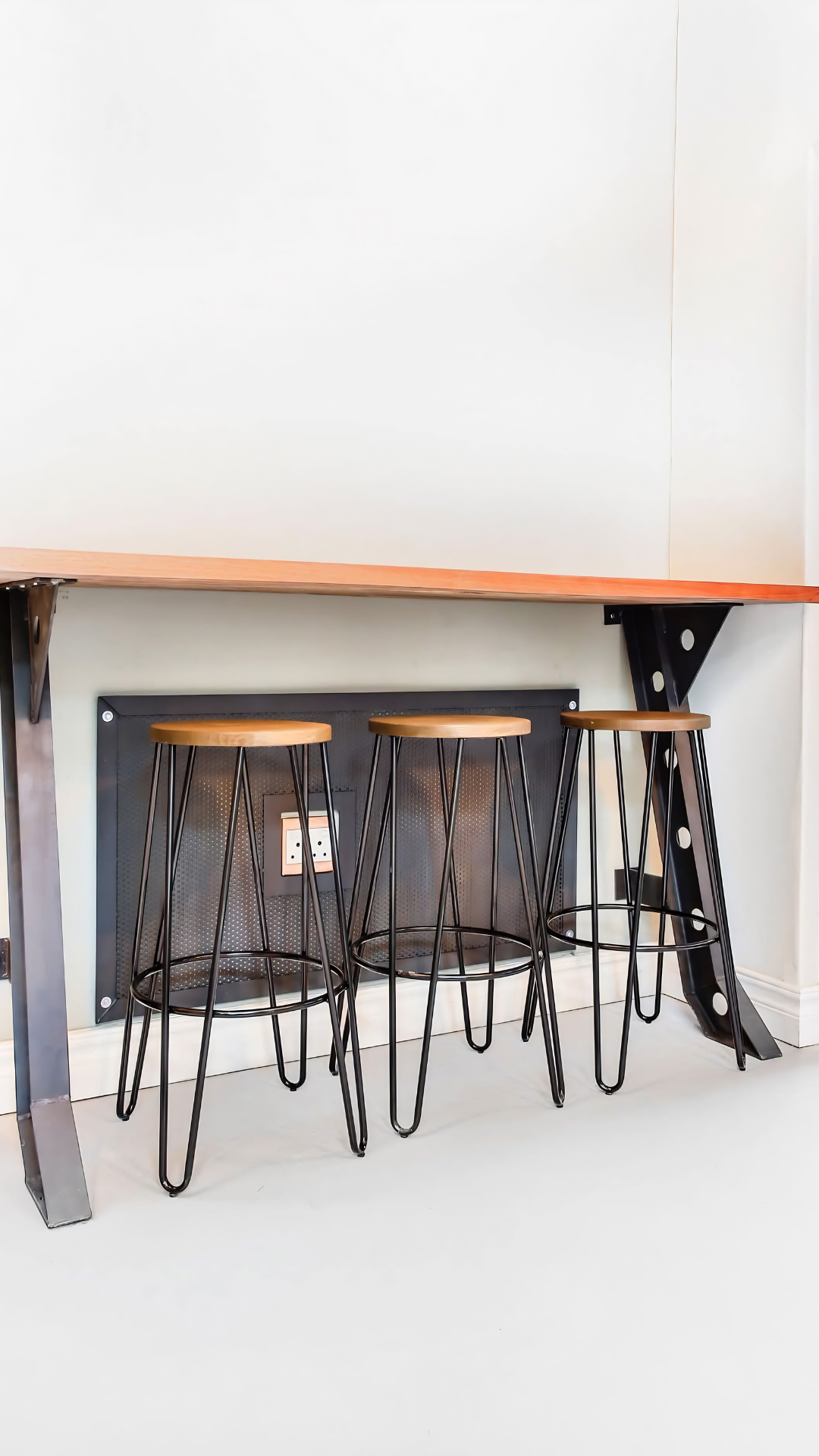 Wall-mounted hardwood bar counter with steel brackets and hairpin stools